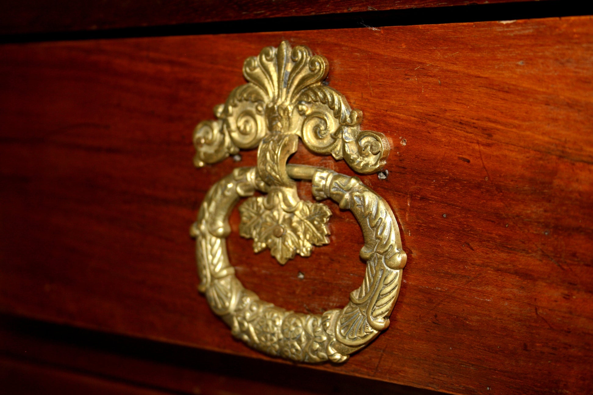 Maniglia in ottone ornato su legno scuro, perfetta per un design vintage casa