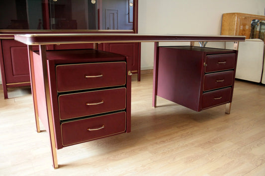Ministerial desk designed by Umberto Mascagni in burgundy faux leather with drawers and brass details.