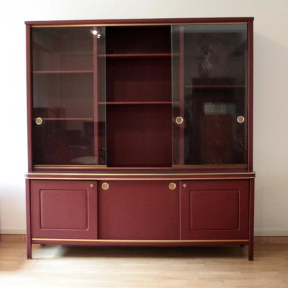 Credensa o libreria a due corpi rivestita in similpelle bordeaux con ante scorrevoli in vetro design italiano d’epoca umberto mascagni negli anni 50