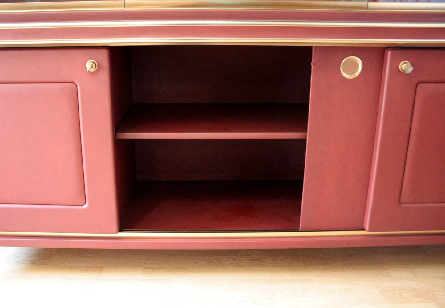 Red cabinet with sliding doors in Set Studio Umberto Mascagni with similpelle bordeaux