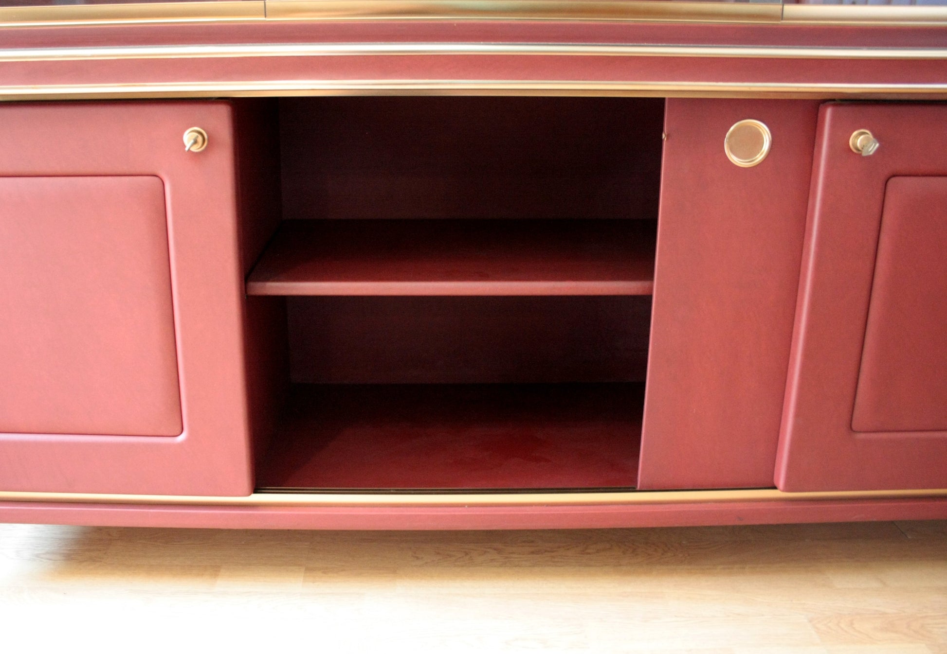 Red cabinet with sliding doors in Set Studio Umberto Mascagni with similpelle bordeaux
